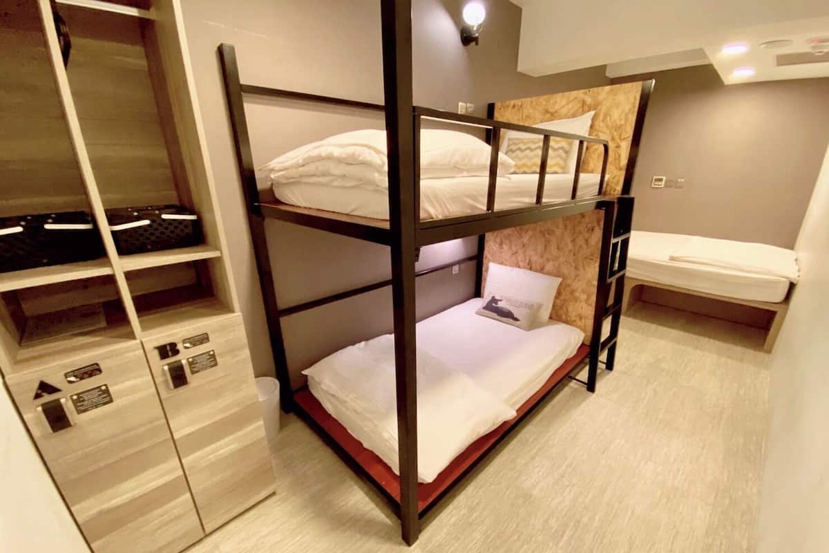 Ein Schlafraum mit Etagenbett, einem hölzernen Kopfteil, einem kleinen Nachttisch und einem Regal mit Aufbewahrungsboxen.