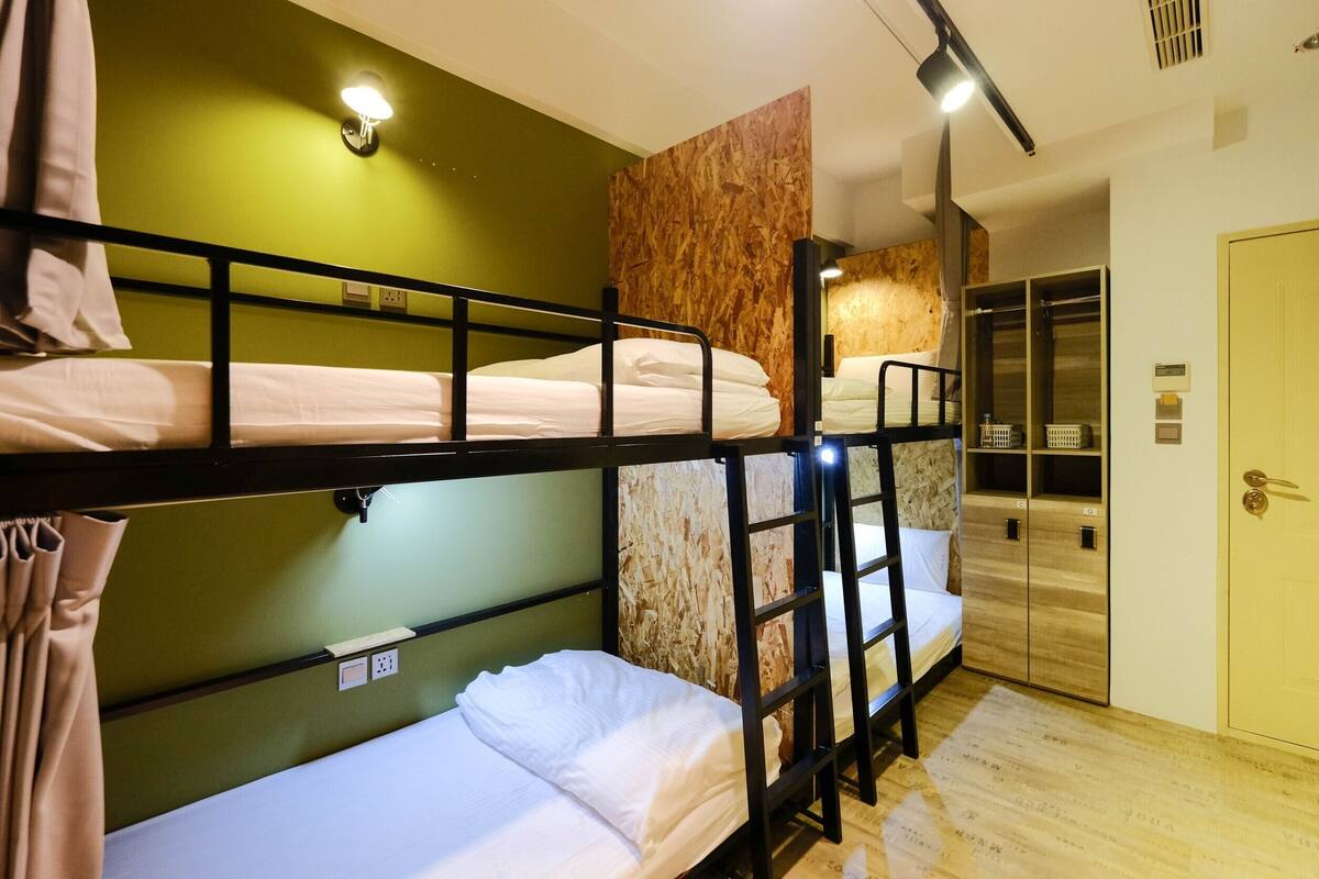 Ein Schlafraum mit Etagenbetten, einer grünen Wand, einer Holzvertäfelung und einem Kleiderschrank mit Spiegel.