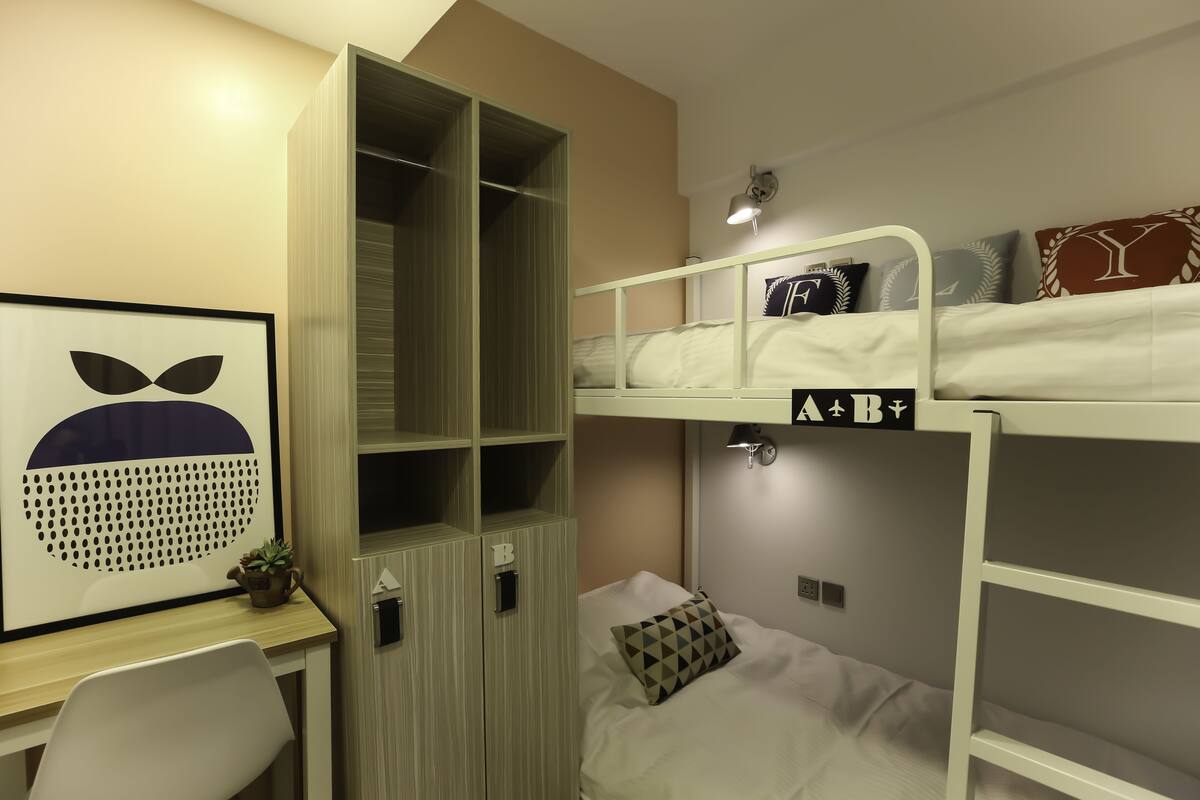 Ein Schlafzimmer mit Etagenbetten, einem Schreibtisch, einem gerahmten Bild und einer kleinen Pflanze.
