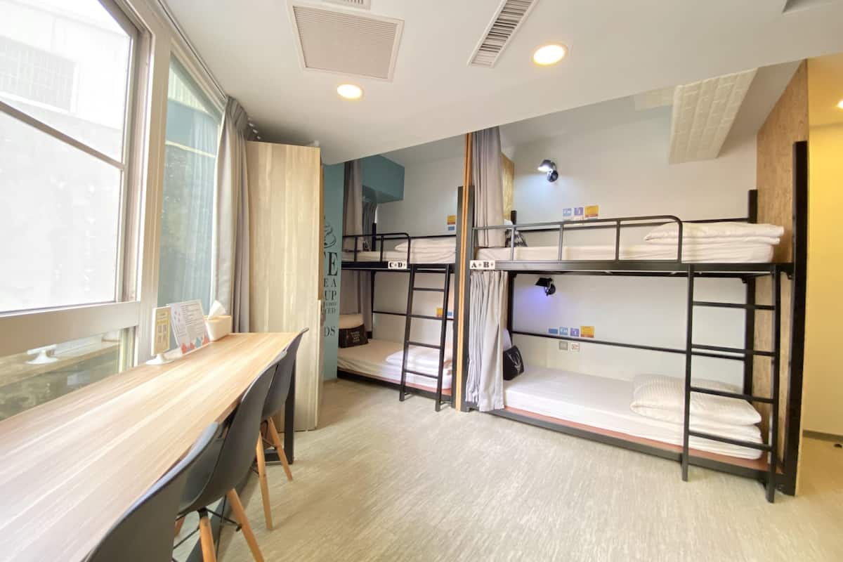 Ein Schlafsaalzimmer mit Etagenbetten, einem Schreibtisch und einem Fenster.