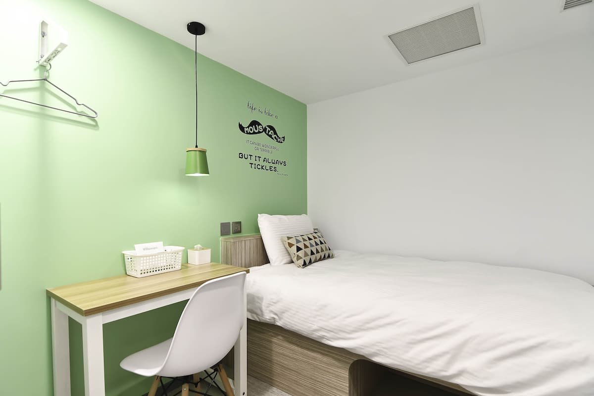 Ein Schlafzimmer mit Bett, Schreibtisch, Stuhl, Wandhänger und einer Wanddekoration.