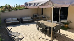 Une terrasse extérieure avec une table et des chaises, un canapé et un espace abrité.