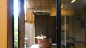 A traditional Japanese room with tatami flooring, a wooden table, and a stone arrangement.