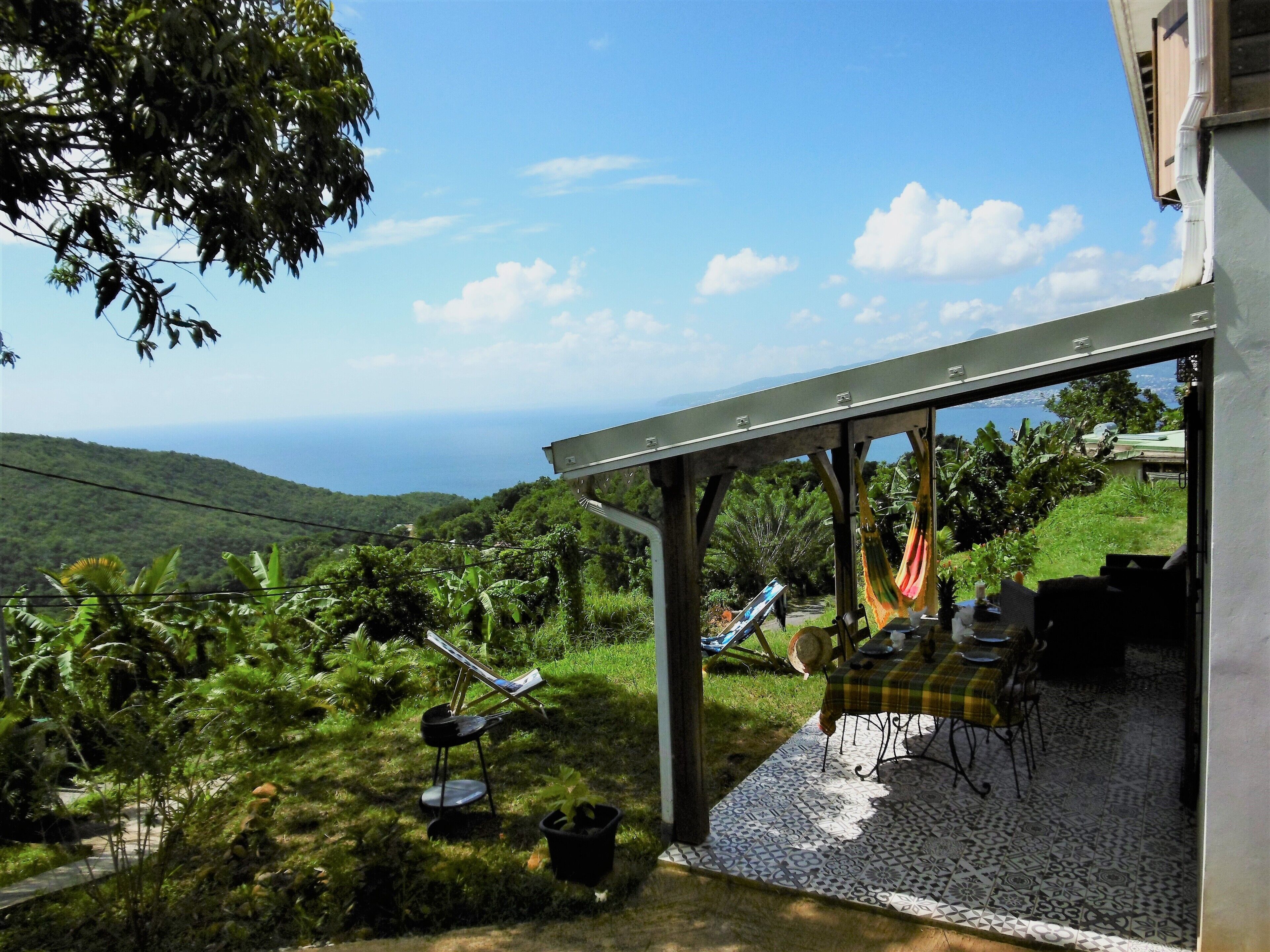 Un patio con mesa y sillas, una hamaca y vista al océano.