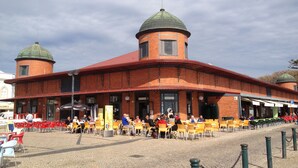 A brick building with two domed towers and a covered outdoor seating area with yellow chairs. - Mar i Terra, the home of your vacation! (olhao)