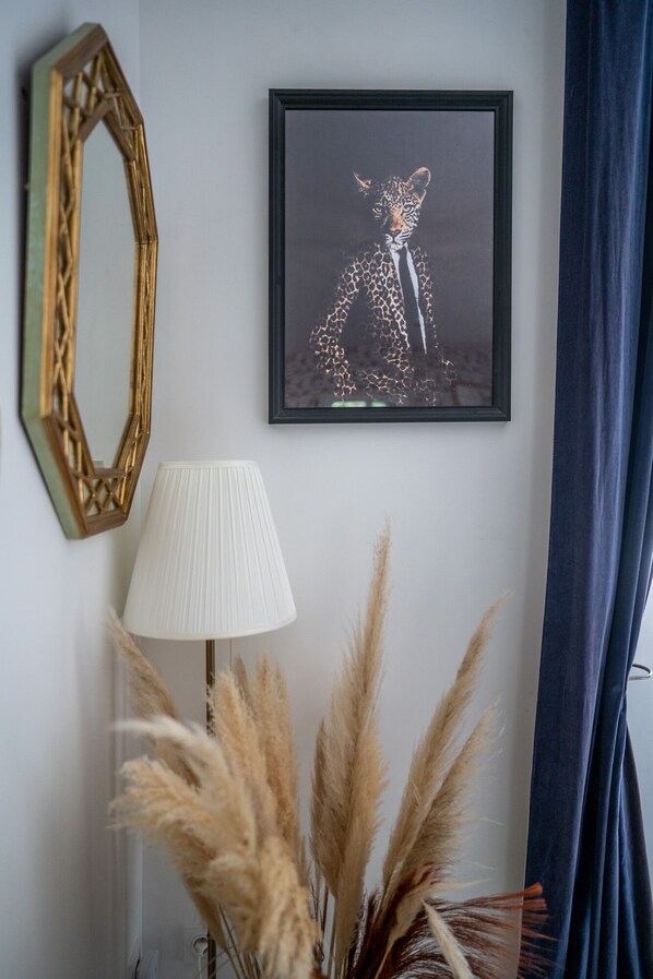 A framed artwork of a leopard, a lamp, and pampas grass on a wall.