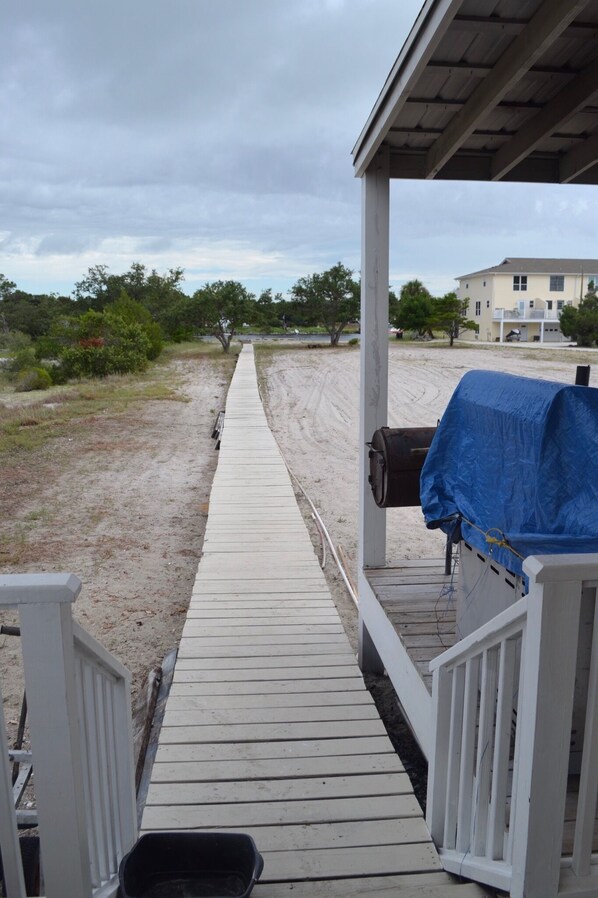 A wooden pier leading to a beach area with a barbecue setup.