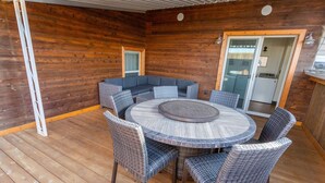 A wooden deck with a round table and wicker chairs, a built-in bench, and a sliding glass door leading to an interior space. - The Loft on Birch, Downtown Walla Walla, sleek modern industrial Condo (Walla Walla)