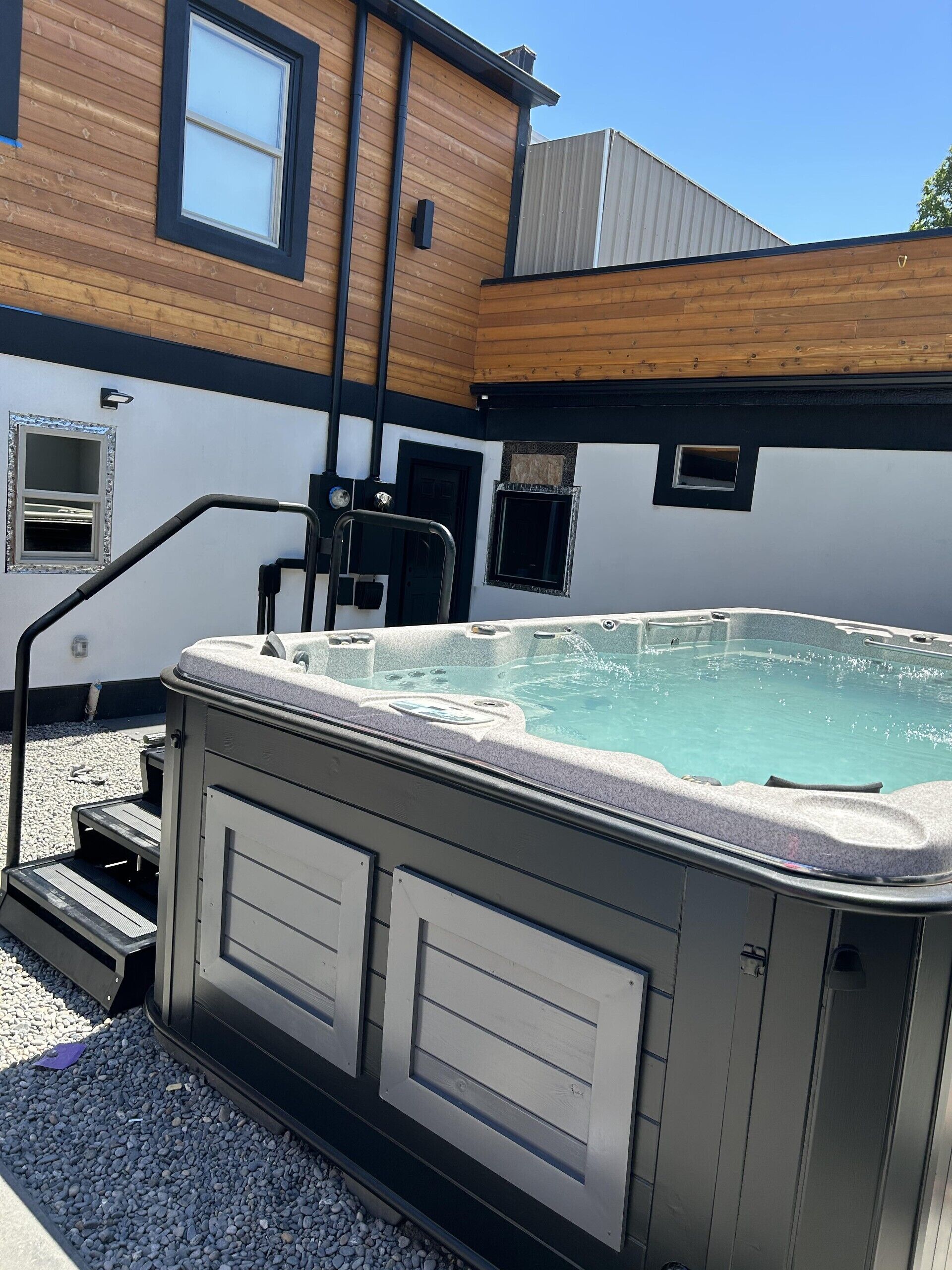 A hot tub with steps leading up to it, surrounded by a gravel area.