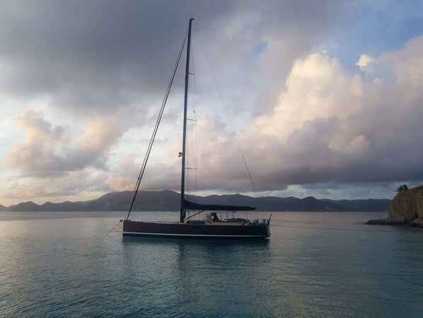 A sailboat on calm waters with mountains in the background.