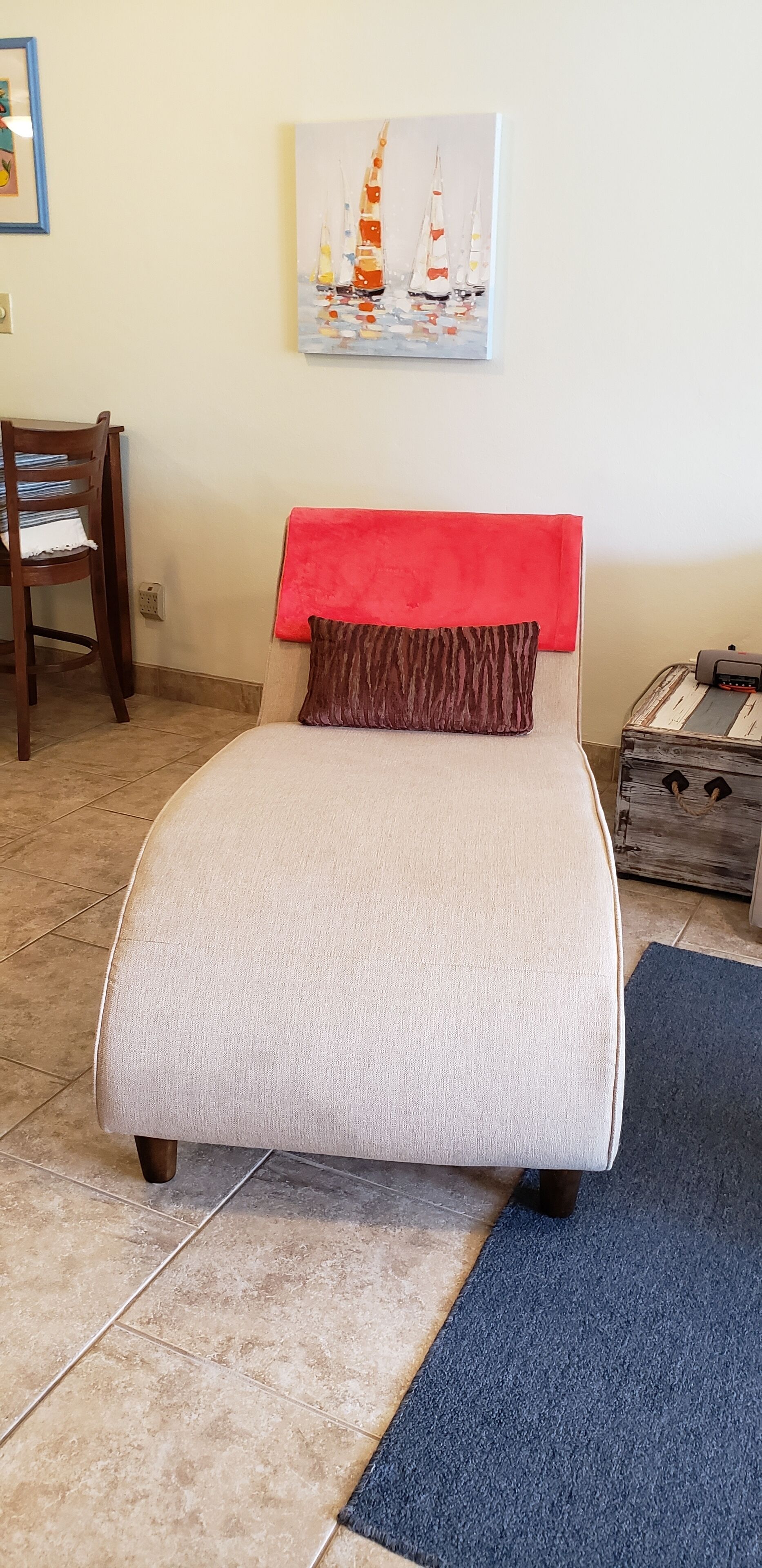 Un letto con una testiera rossa, un cuscino marrone e una coperta beige.