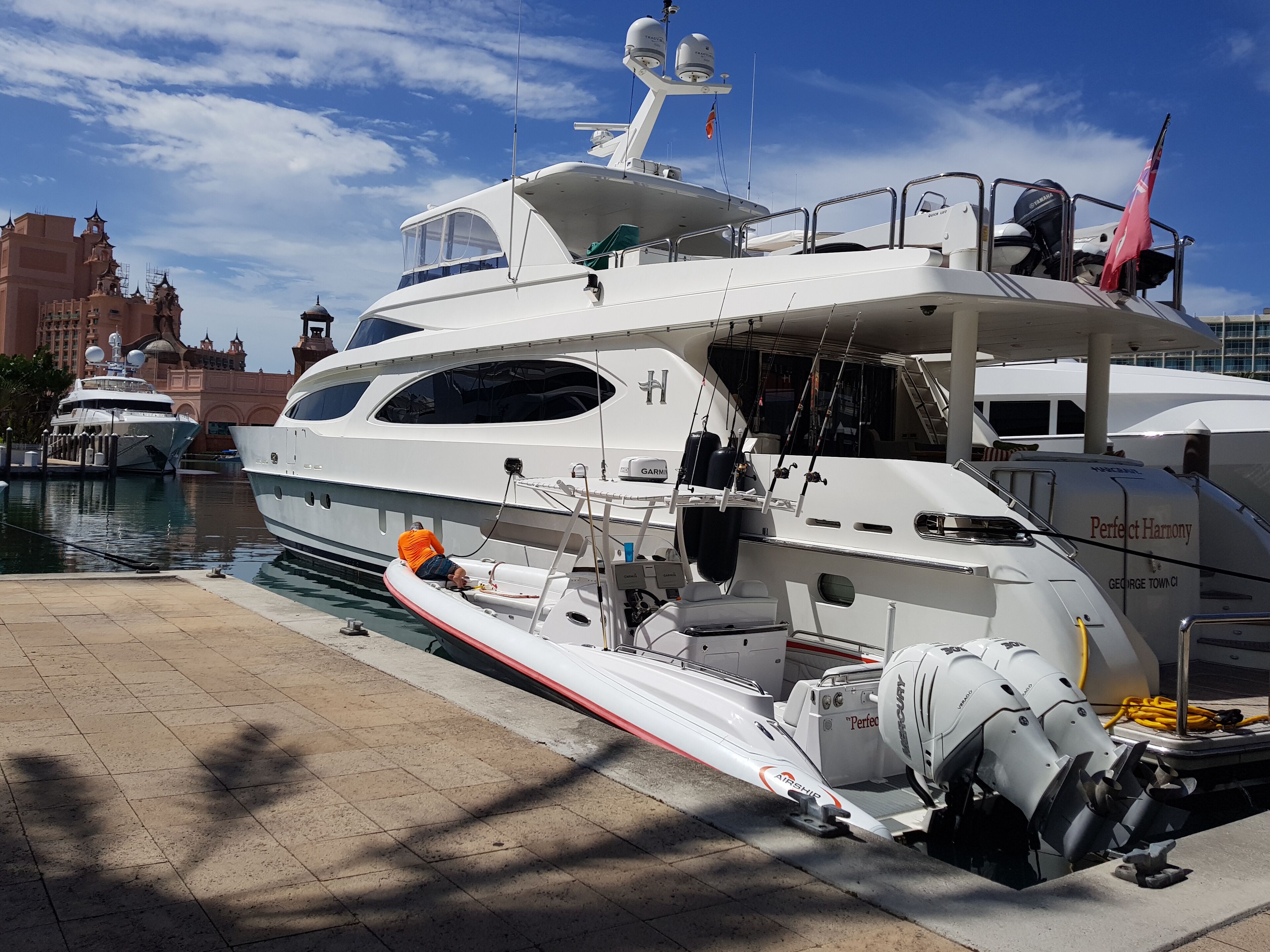A large yacht docked at a marina with a modern building in the background.