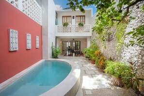 A courtyard with a swimming pool, a dining area, and potted plants.