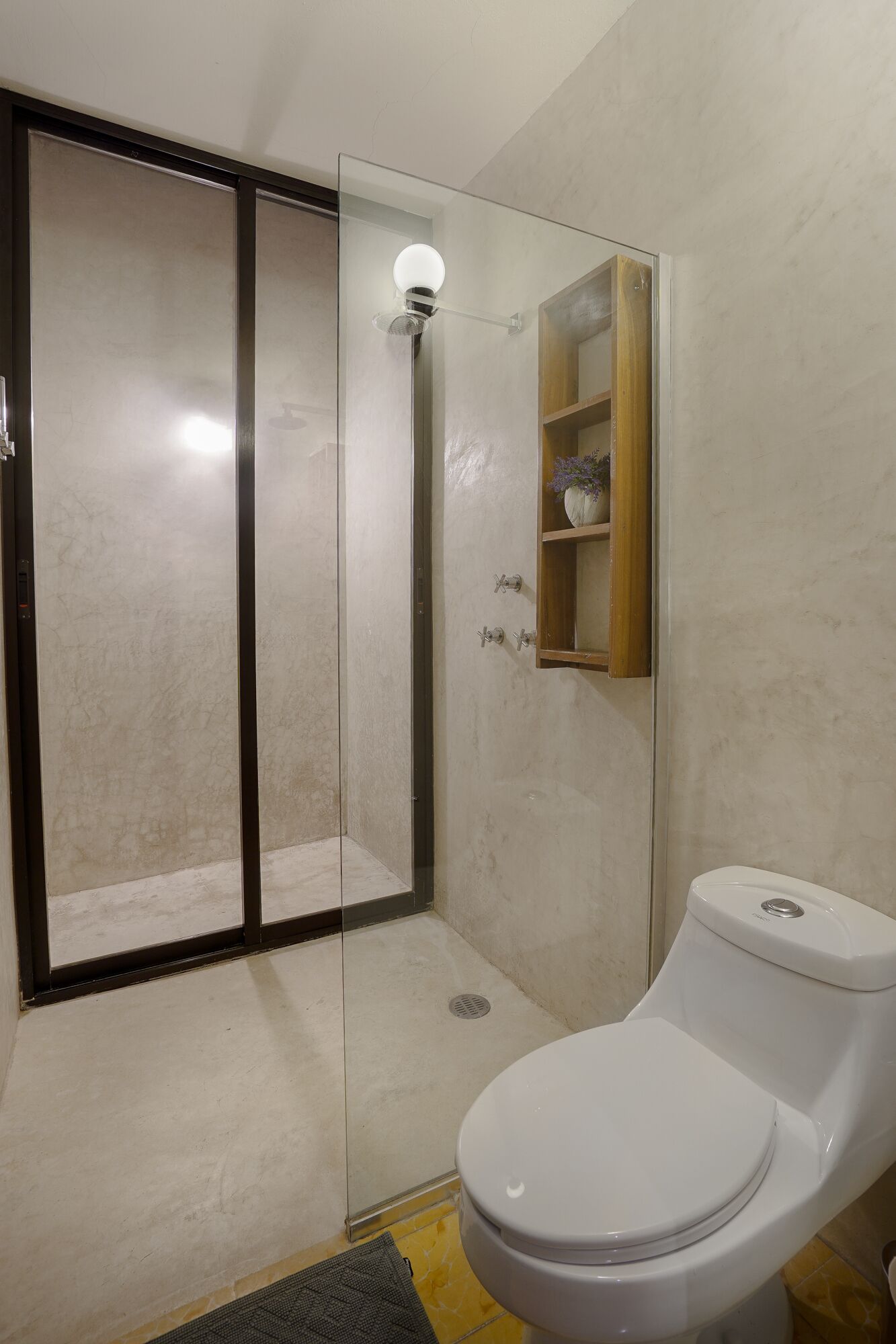 A bathroom with a glass-enclosed shower, a toilet, and a wooden medicine cabinet.
