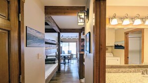 Un pasillo con pisos de madera, una cama, una zona de comedor y una cocina con encimera de granito.
