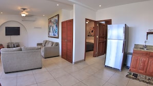 Un salón espacioso con un sofá gris, un televisor de pantalla plana y un cuadro en la pared.