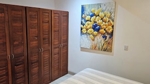 Un dormitorio con cama, armario de madera y un cuadro en la pared.