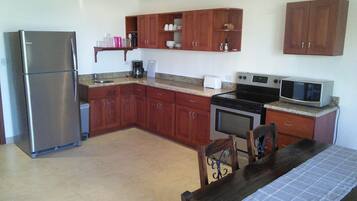 A kitchen with wooden cabinets, a stainless steel refrigerator, a microwave, and a stove.