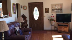 A living room with a leather sofa, a wooden coffee table, a TV stand, and a door with a stained glass window.