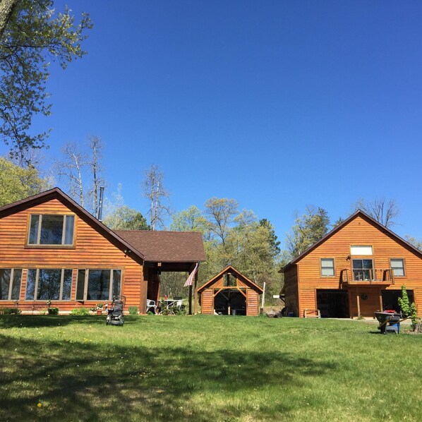 A two-story wooden cabin with a covered porch and a garage. - TWO BEATIFUL CABINS  IN THE HEART OF RECREATION: (Spooner)