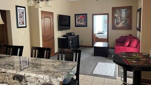 A living room with a dining area, a TV mounted on the wall, and a ceiling fan.