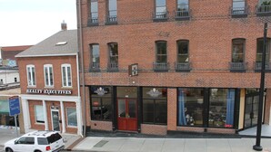 A brick building with a 'REALTY EXECUTIVES' sign on the ground floor and a 'MINGLEWOOD BREWERY' sign above the entrance.