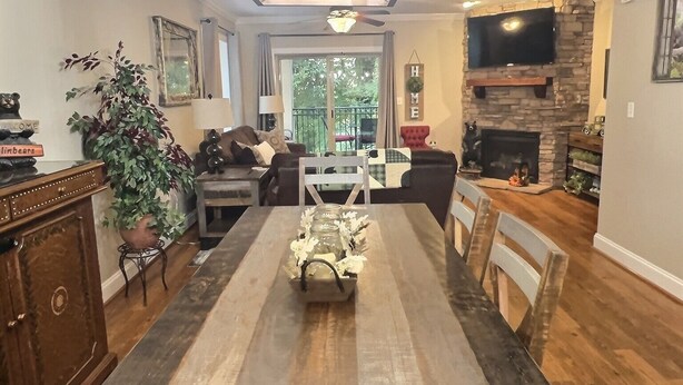 A spacious living room with a large wooden dining table, a fireplace, and a television mounted on a stone wall. - Beautiful Downtown Gatlinburg Smokey mountain condo  (Gatlinburg)