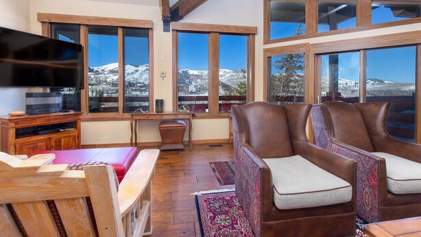 A spacious living room with a large window offering a mountain view, a wooden desk, and leather armchairs. - New Remodeled interior plus outside updated in Upper DV walk to Silver Lake (DEER VALLEY)
