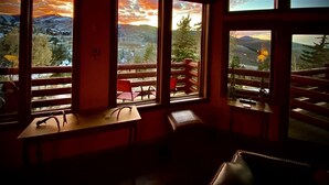 A room with large windows offering views of a mountainous landscape. There are wooden tables and chairs inside. - New Remodeled interior plus outside updated in Upper DV walk to Silver Lake (DEER VALLEY)