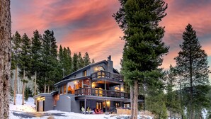 A modern two-story lodge with a balcony, surrounded by tall pine trees and a snowy landscape. - Spacious 3-Story Breck Mountain Home - Pet-Friendly, Peak 10 Views & Hot Tub (Brekenridge)