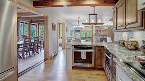 A spacious kitchen with wooden beams, granite countertops, and a large island. - Spacious 3-Story Breck Mountain Home - Pet-Friendly, Peak 10 Views & Hot Tub (Brekenridge)