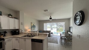 Una cocina moderna con alacenas blancas, lavavajillas y un comedor con mesa y sillas.