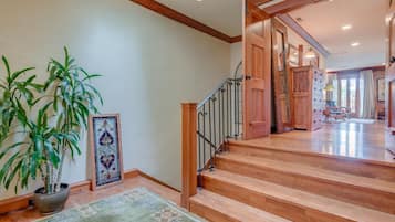 Un escalier avec des marches en bois et une rampe en métal menant à une pièce dotée d’une grande fenêtre et d’un fauteuil.