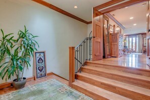 A staircase with wooden steps and a metal railing leading to a room with a large window and a chair.
