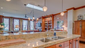 A spacious kitchen with granite countertops, wooden cabinets, and a large island with a sink. - Incredible Luxury Loft in Historic Downtown McMinnville (McMinnville)