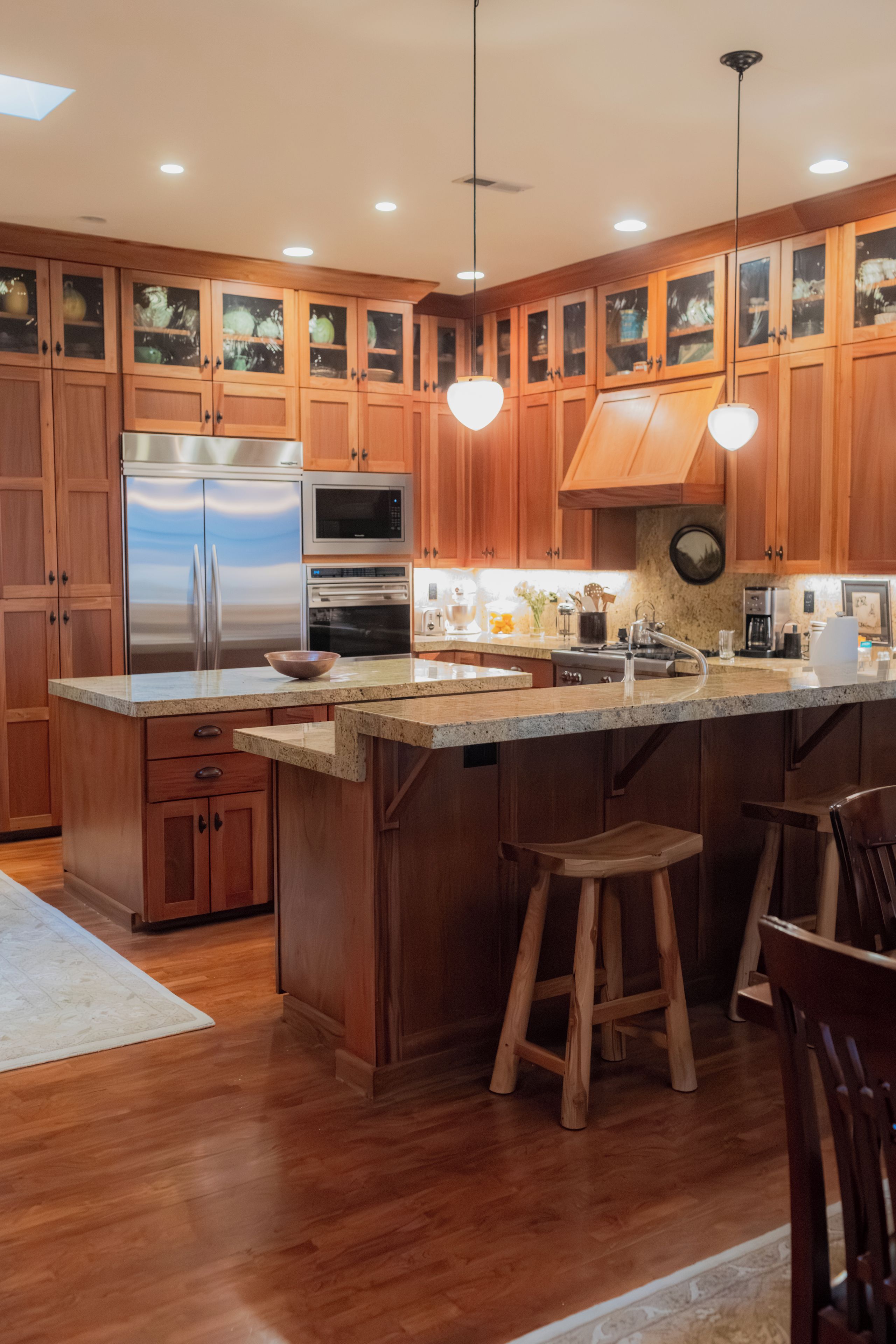 A modern kitchen with wooden cabinets, stainless steel appliances, and a central island with stools.