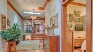 A hallway with wooden flooring, a potted plant, a desk with a vase of flowers, and a staircase leading to another room. - Incredible Luxury Loft in Historic Downtown McMinnville (McMinnville)