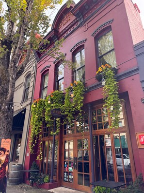 En bygning med en rød facade, store vinduer og et skilt, der viser 'La Ramada Restaurant & Bar'.