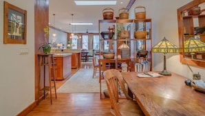A spacious kitchen with wooden cabinetry, a central island, and a dining area with wooden chairs and a table. - Incredible Luxury Loft in Historic Downtown McMinnville (McMinnville)