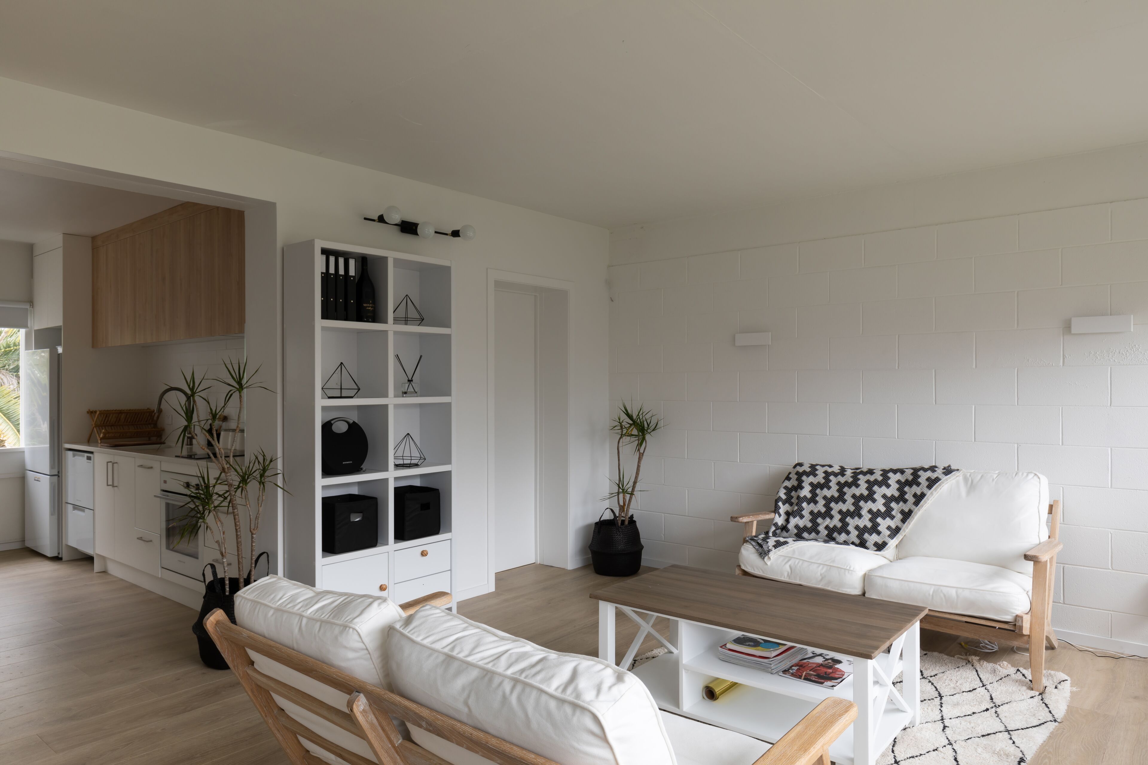 A modern living room with a white sofa, wooden coffee table, and a white brick wall.