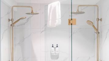 A glass-enclosed shower with gold fixtures and marble walls.