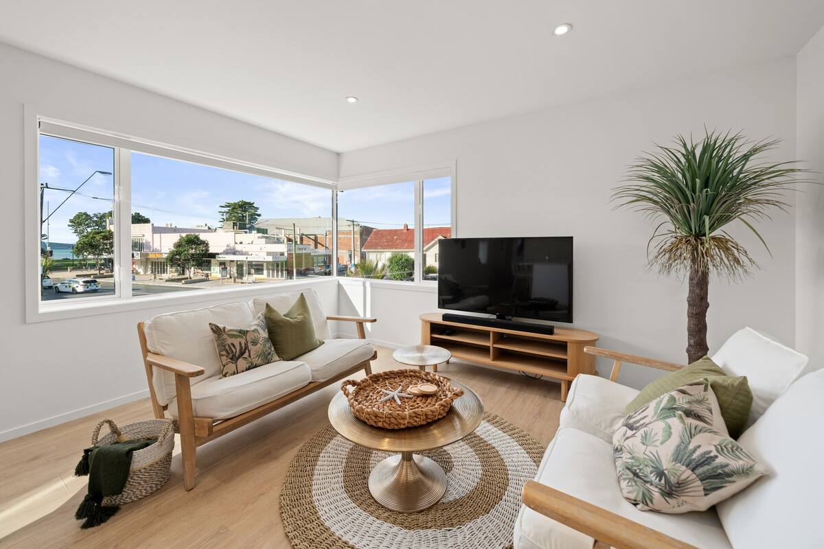 A modern living room with a sofa, TV, and a view of the city.