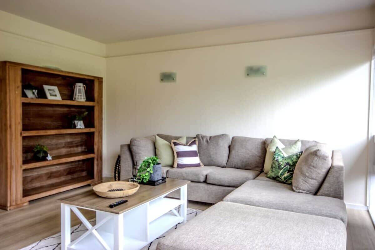 A living room with a sectional sofa, a wooden bookshelf, and a coffee table.