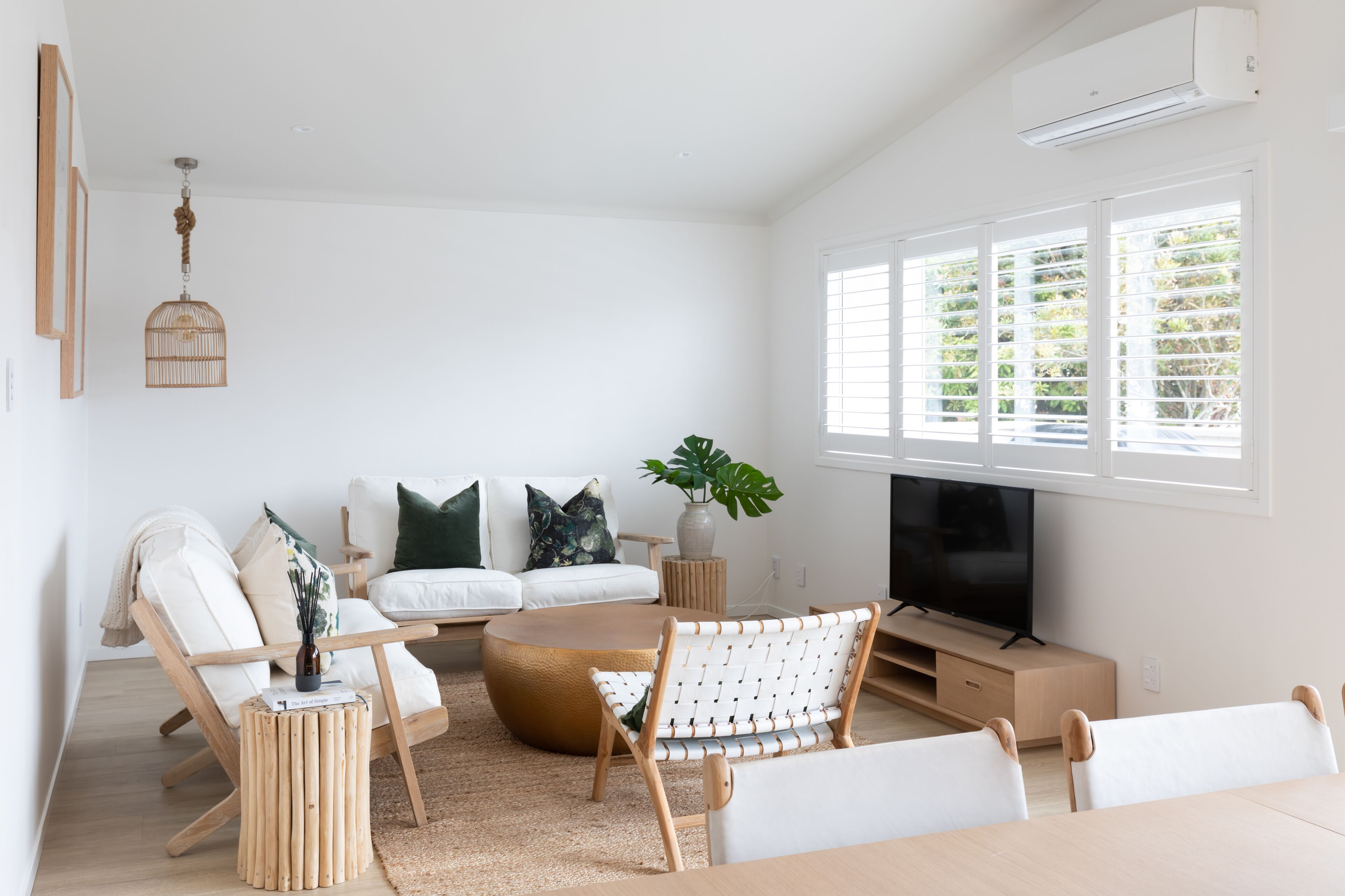 Un salon moderne avec un canapé, des fauteuils, une table basse et un téléviseur.