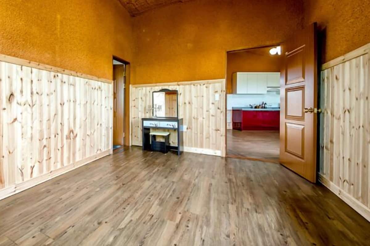 A spacious room with wooden paneling on the walls and a wooden floor.