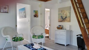 Quarto com cadeiras de vime, cômoda branca e escada.