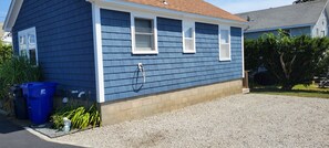 A blue house with a gravel driveway and a small garden area. - Adorable Cottage Walk Across Street to First Beach, Winter min stay 9 mos (Middletown)