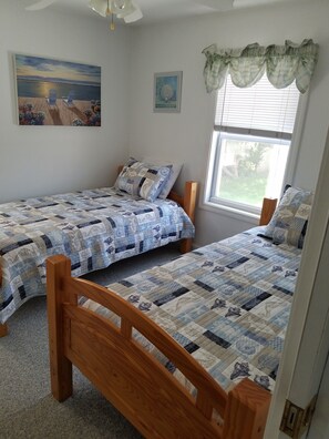 A bedroom with two wooden beds, a ceiling fan, a window with blinds, and artwork on the walls. - Adorable Cottage Walk Across Street to First Beach, Winter min stay 9 mos (Middletown)