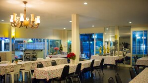 A restaurant with multiple tables and chairs, a chandelier, and a view of the street outside. - PK Resort Pattaya (Pattaya)