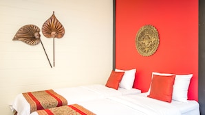 A double bed with white bedding and red accents, a red accent wall, and two wall-mounted decorative fans. - PK Resort Pattaya (Pattaya)